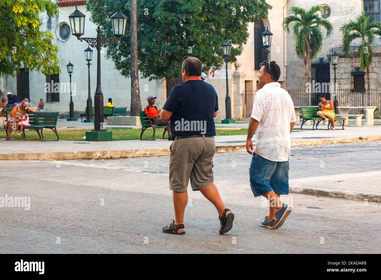 Dos hombres caminando en medio de una calle de la ciudad. Estilo de vida de la gente real por una pequeña parquette en la esquina Foto de stock