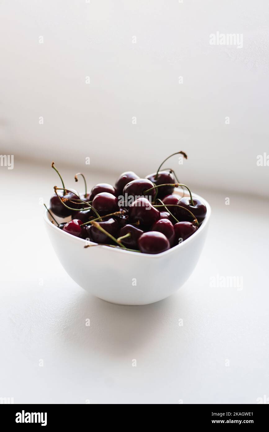 Cerezas maduras frescas sobre un plato sobre un fondo blanco. Vitaminas y nutrición saludable Foto de stock