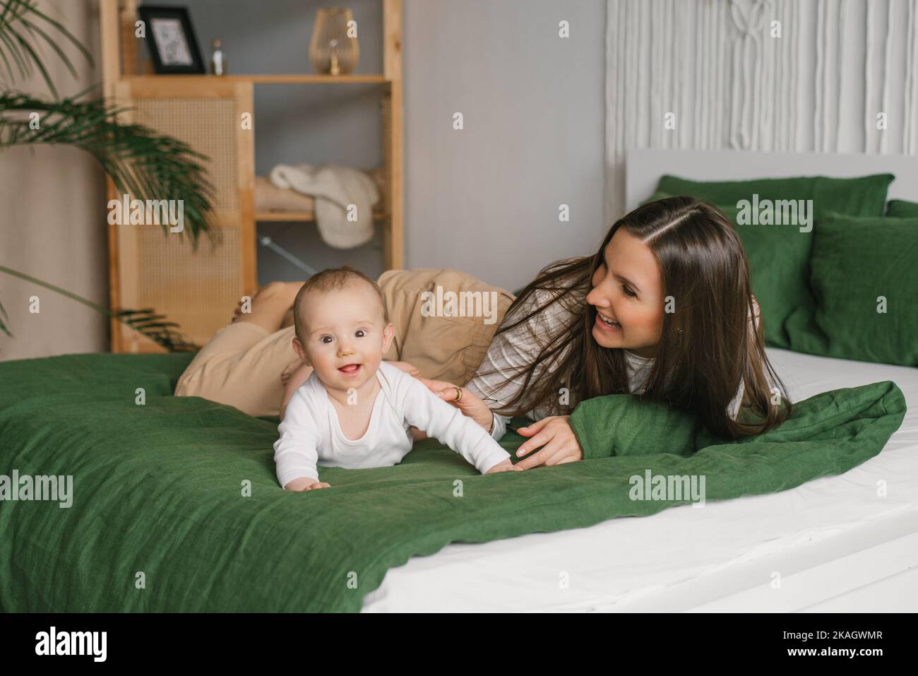 Divertirse con la mamá y el bebé en la cama en casa Foto de stock