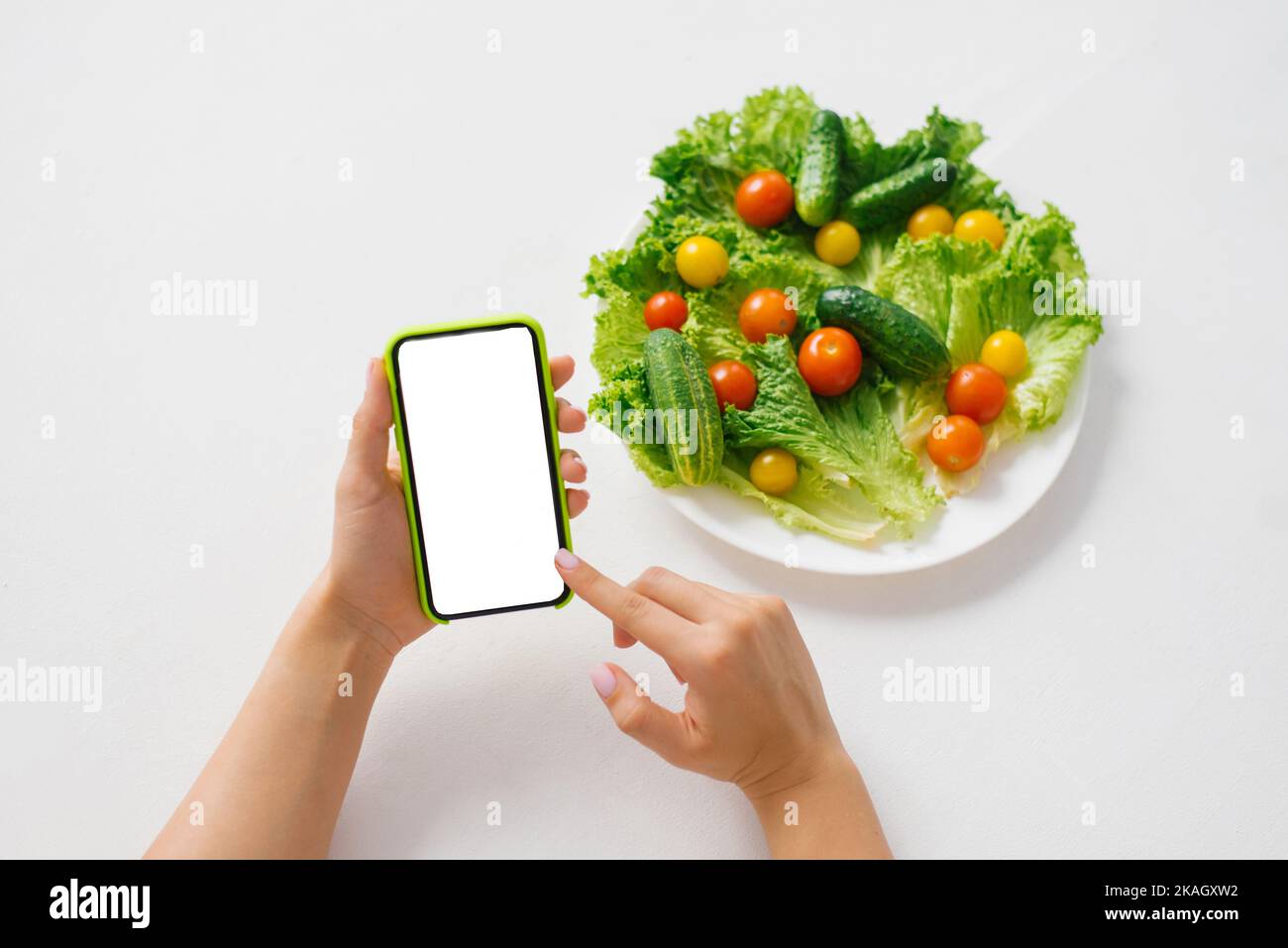 Primer plano de las manos de una joven con la aplicación móvil de simulación de smartphone para completar su dieta diaria, comprobando datos nutricionales y calorías Foto de stock