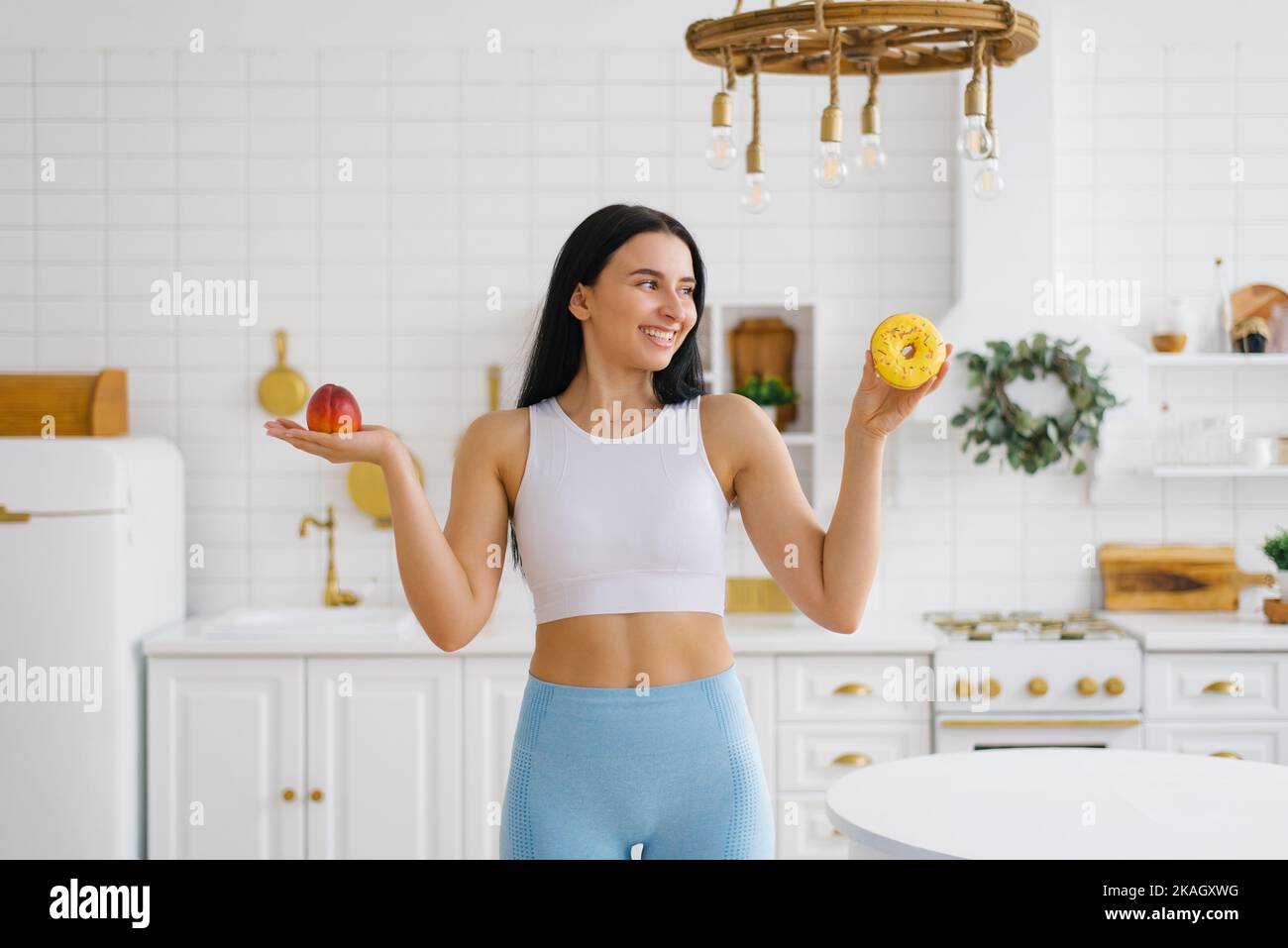 Una mujer joven elige entre una fruta de melocotón y un donut. El concepto de dieta y alimentación saludable Foto de stock