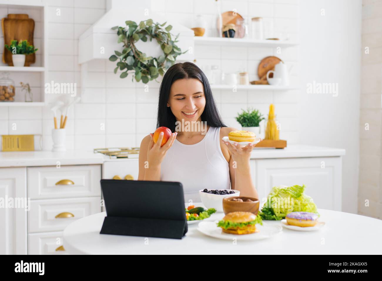 La nutricionista feliz de la mujer lleva a cabo una lección en línea o conferencia en la cocina sobre el tema de la alimentación sana y de la pérdida del peso Foto de stock