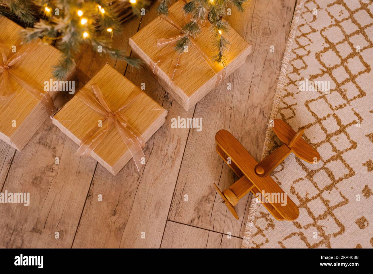 Juguete de avión de madera y regalos cerca del árbol de Navidad. El concepto de descanso y viajes de invierno para las vacaciones Foto de stock