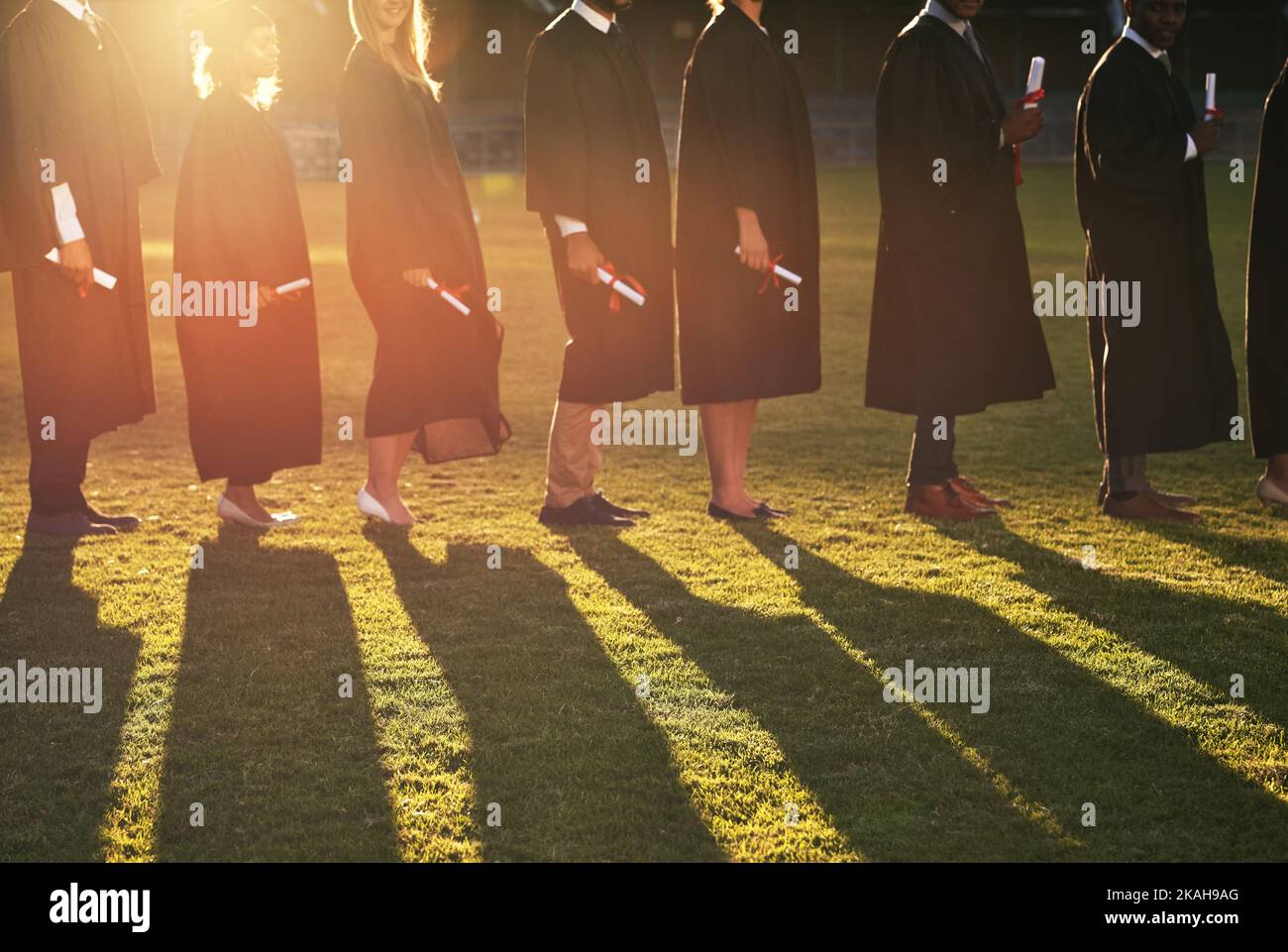 Inspire a otros a seguir sus pasos. Un grupo de estudiantes universitarios juntos el día de la graduación. Foto de stock