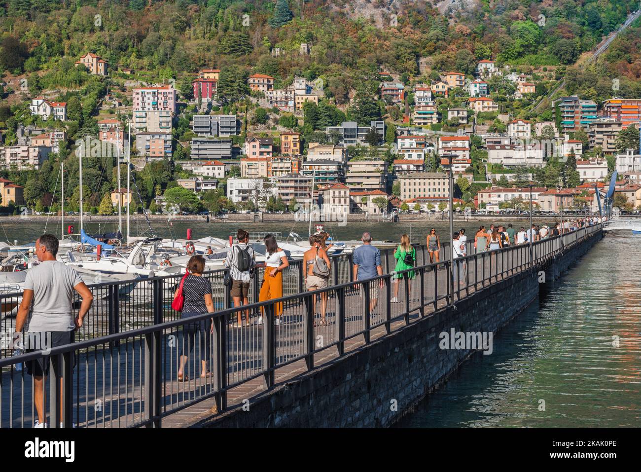 Puerto de la ciudad de Como, vista en verano de la gente en la pasarela que lleva a la obra de arte Life Electric de Daniel Libeskind en el puerto de la ciudad de Como, Italia Foto de stock