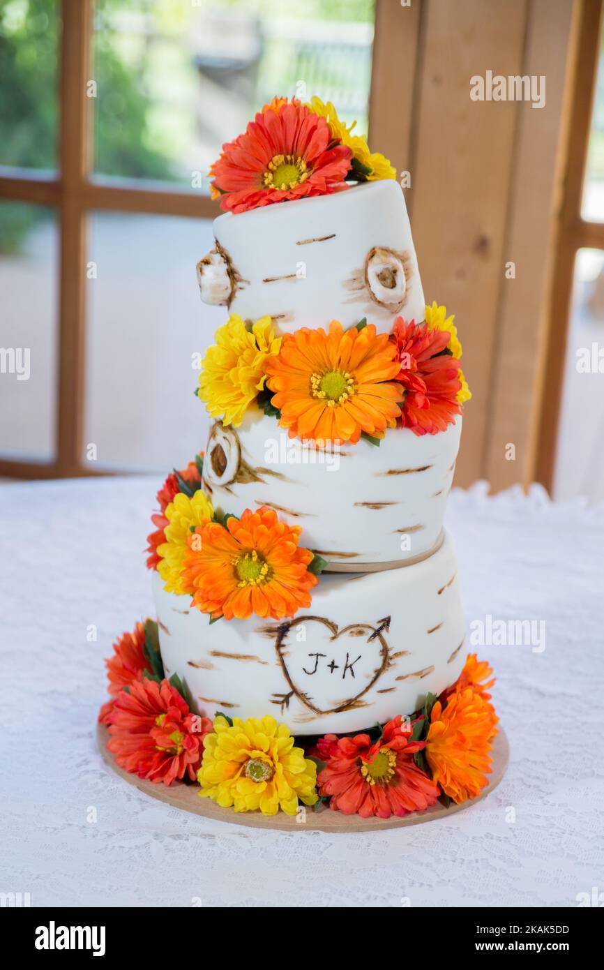 Un pastel de tres niveles de boda con las iniciales J y K en él y girasoles rojo  amarillo-anaranjado brillante Fotografía de stock - Alamy
