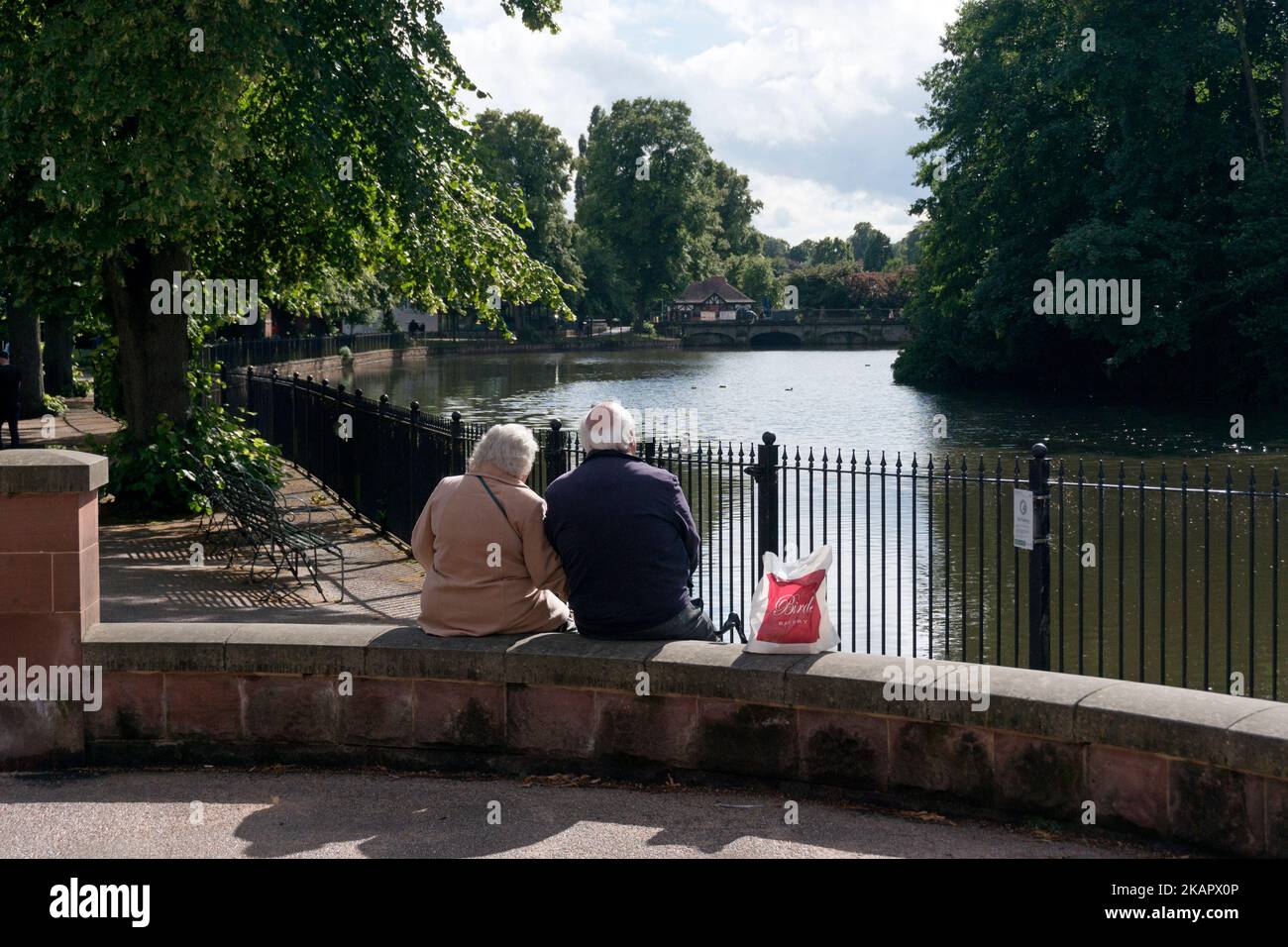 Pareja mayor sentada junto a Minster Pool, Lichfield, Staffordshire Foto de stock
