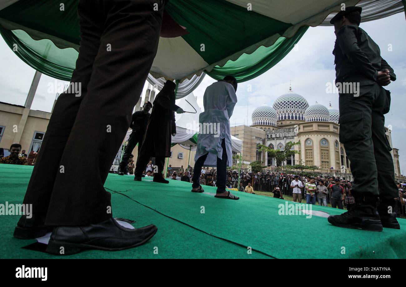 Un hombre acehnés es azotado ante el público por violar la ley sharia en la mezquita del Centro Islámico Lhokseumawe, en la provincia de Aceh, Indonesia, el 22 de diciembre de 2017. Los azotes son una forma de castigo impuesta en Aceh por violar la ley islámica de la sharia. (Foto de Fachrul Reza/NurPhoto) Foto de stock