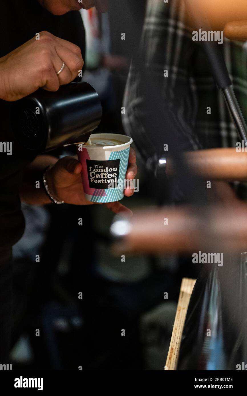 Captura de primer plano para barista vertiendo leche en un primer plano de concentración de café Foto de stock