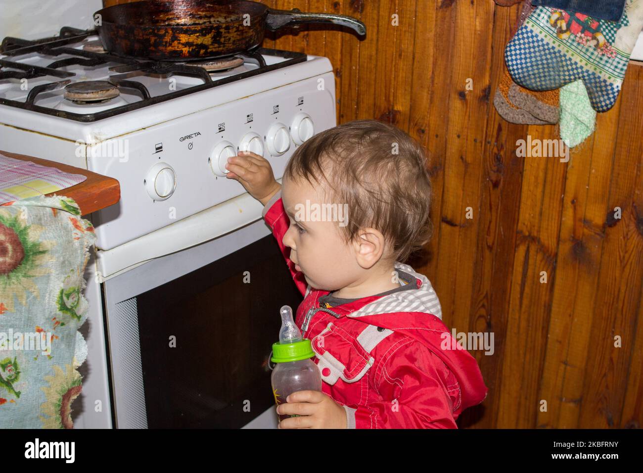 El niño solo juega en la cocina con una estufa de gas. Foto de stock