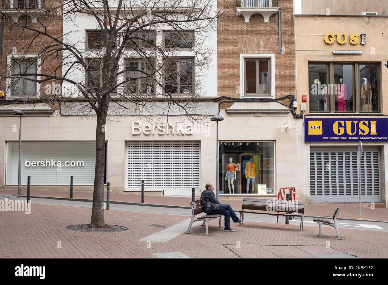 Un hombre descansando en un banco con tiendas Bershka y Gusi cerradas  después del estado de alarma impuesto por el gobierno español y medida de  cierre de la población de Cataluña por