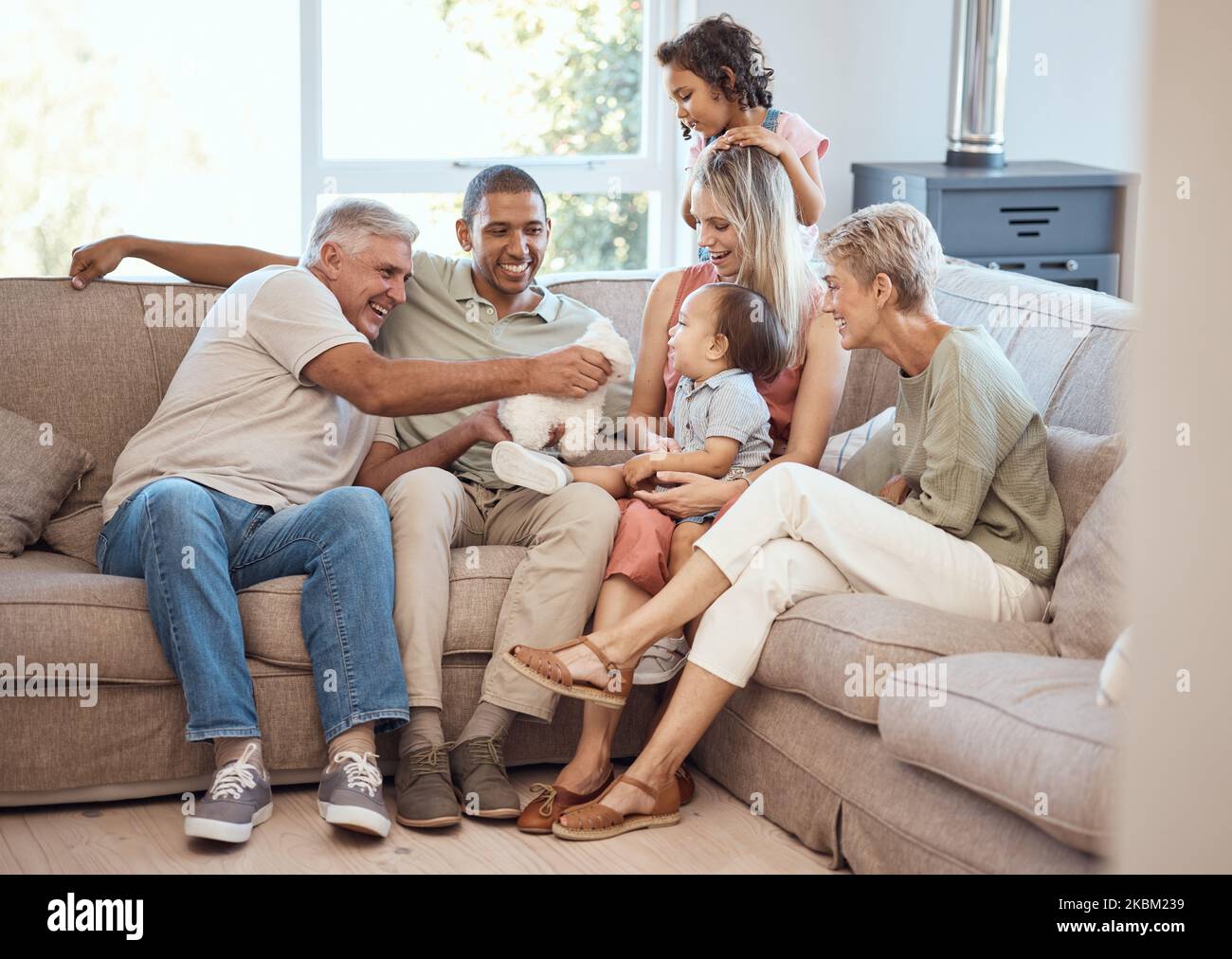 Feliz, con amor y gran familia relajándose en el sofá juntos en la sala de estar de su casa. Felicidad, abuelos y padres con niños jugando Foto de stock
