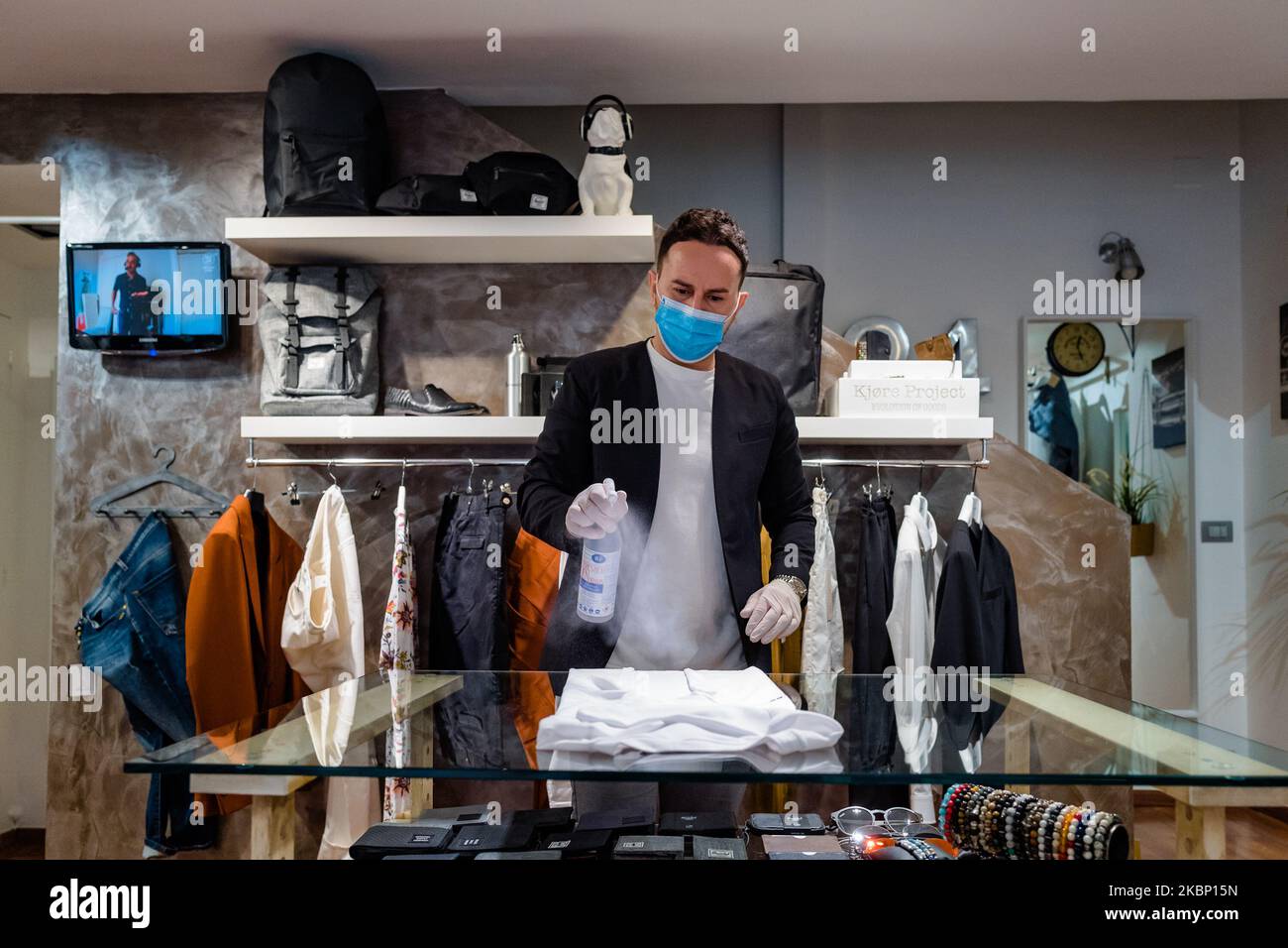 El dueño de una tienda de ropa desinfecta la ropa, en Molfetta, Italia, el 19 mayo de 2020. A partir del de mayo también se reabrieron las tiendas de ropa