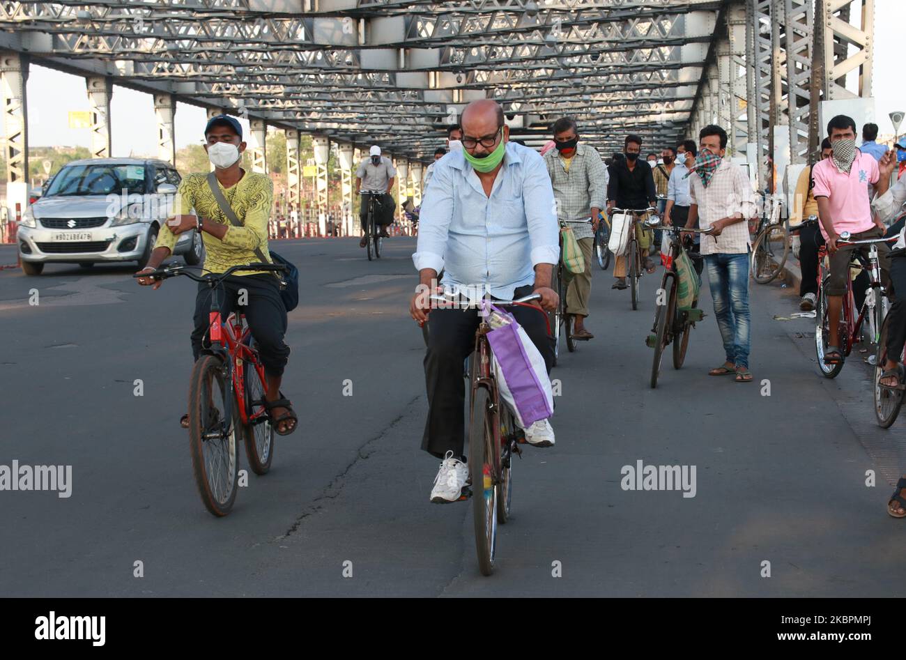 Los viajeros viajan en sus bicicletas por el puente Howrah sobre el río  Ganga el Día Mundial de la Bicicleta el 3 de junio de 2020 en Kolkata,  India. Se abrieron más