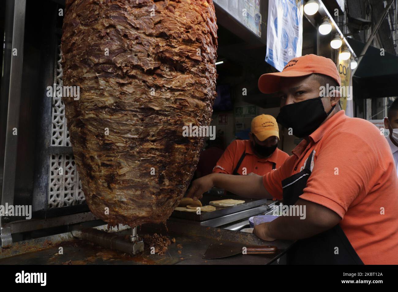 Un taquero con máscaras que cortan carne para el pastor en un  establecimiento de Ciudad de México, esperando a los clientes durante un  cambio de semáforo rojo a naranja en el Covid-19. (