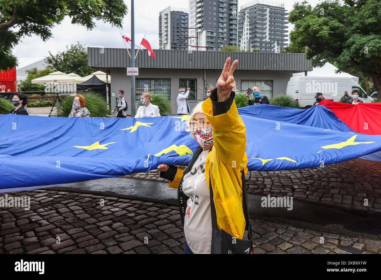 Una mujer que muestra un signo de victoria con banderas gigantes polacas y de la UE se ve en Gdansk, Polonia, el 31 de agosto de 2020, Lech Walesa y otros líderes y miembros de los partidos de oposición celebran el aniversario de los Acuerdos de Agosto en Gdansk en la Plaza de Solidaridad de Gdansk (Foto de Michal Fludra/NurPhoto) Foto de stock