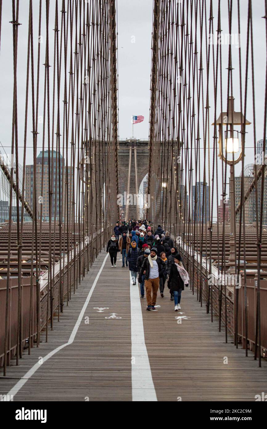 Cientos de personas en el Puente de Brooklyn en la ciudad de Nueva York en los Estados Unidos, visto durante un día nublado con turistas y lugareños en él. El famoso puente, un punto de referencia para Nueva York y los Estados Unidos de América es un puente suspendido de cable híbrido que abarca el río East entre los distritos de Manhattan y Brooklyn. El histórico puente de Nueva York fue construido entre 1869 y 1883. Nueva York, EE.UU. El 13 de febrero de 2020 (Foto de Nicolas Economou/NurPhoto) Foto de stock