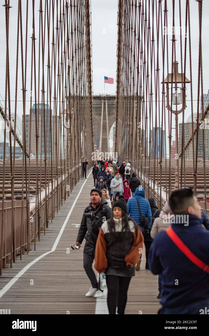 Cientos de personas en el Puente de Brooklyn en la ciudad de Nueva York en los Estados Unidos, visto durante un día nublado con turistas y lugareños en él. El famoso puente, un punto de referencia para Nueva York y los Estados Unidos de América es un puente suspendido de cable híbrido que abarca el río East entre los distritos de Manhattan y Brooklyn. El histórico puente de Nueva York fue construido entre 1869 y 1883. Nueva York, EE.UU. El 13 de febrero de 2020 (Foto de Nicolas Economou/NurPhoto) Foto de stock