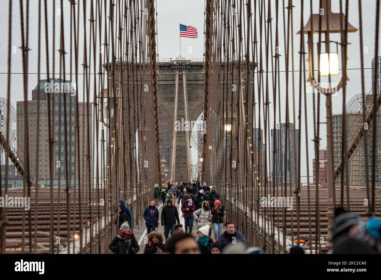 Cientos de personas en el Puente de Brooklyn en la ciudad de Nueva York en los Estados Unidos, visto durante un día nublado con turistas y lugareños en él. El famoso puente, un punto de referencia para Nueva York y los Estados Unidos de América es un puente suspendido de cable híbrido que abarca el río East entre los distritos de Manhattan y Brooklyn. El histórico puente de Nueva York fue construido entre 1869 y 1883. Nueva York, EE.UU. El 13 de febrero de 2020 (Foto de Nicolas Economou/NurPhoto) Foto de stock