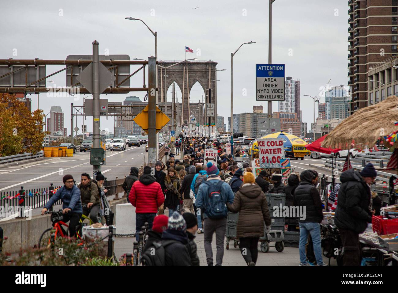 La gente entre ellos muchos turistas y el tráfico con los coches del puente de Brooklyn en la ciudad de Nueva York en los Estados Unidos como visto durante un día nublado con turistas y locales en él. El famoso puente, un punto de referencia para Nueva York y los Estados Unidos de América es un puente suspendido de cable híbrido que abarca el río East entre los distritos de Manhattan y Brooklyn. El histórico puente de Nueva York fue construido entre 1869 y 1883. Nueva York, EE.UU. El 13 de febrero de 2020 (Foto de Nicolas Economou/NurPhoto) Foto de stock