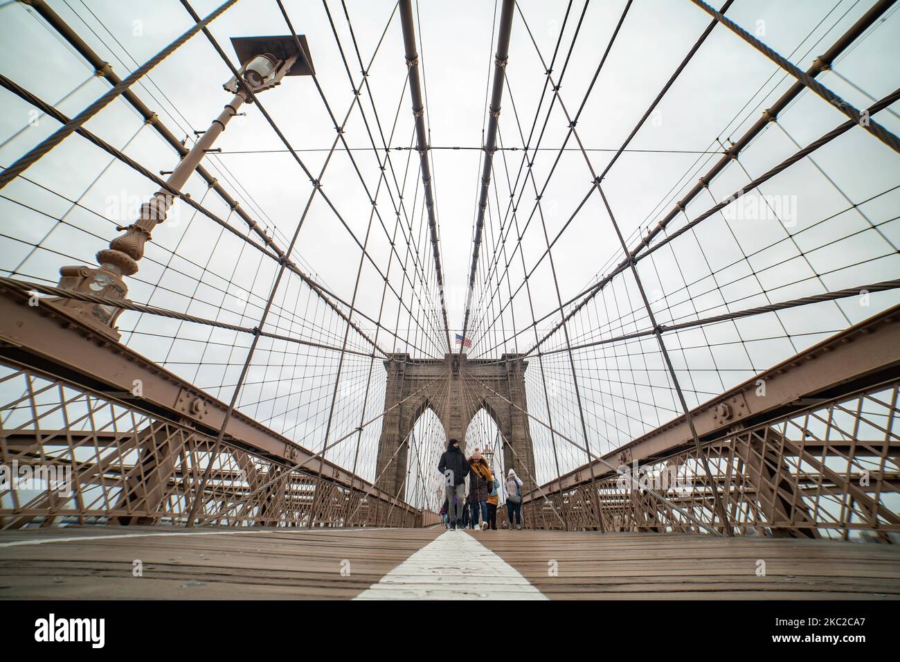 El puente de Brooklyn en la ciudad de Nueva York en los Estados Unidos, visto durante un día nublado con turistas y lugareños en él. El famoso puente, un punto de referencia para Nueva York y los Estados Unidos de América es un puente suspendido de cable híbrido que abarca el río East entre los distritos de Manhattan y Brooklyn. El histórico puente de Nueva York fue construido entre 1869 y 1883. Nueva York, EE.UU. El 13 de febrero de 2020 (Foto de Nicolas Economou/NurPhoto) Foto de stock