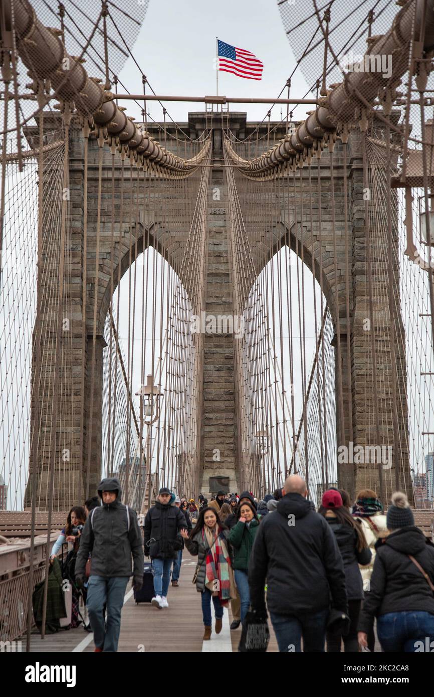 El puente de Brooklyn en la ciudad de Nueva York en los Estados Unidos, visto durante un día nublado con turistas y lugareños en él. El famoso puente, un punto de referencia para Nueva York y los Estados Unidos de América es un puente suspendido de cable híbrido que abarca el río East entre los distritos de Manhattan y Brooklyn. El histórico puente de Nueva York fue construido entre 1869 y 1883. Nueva York, EE.UU. El 13 de febrero de 2020 (Foto de Nicolas Economou/NurPhoto) Foto de stock