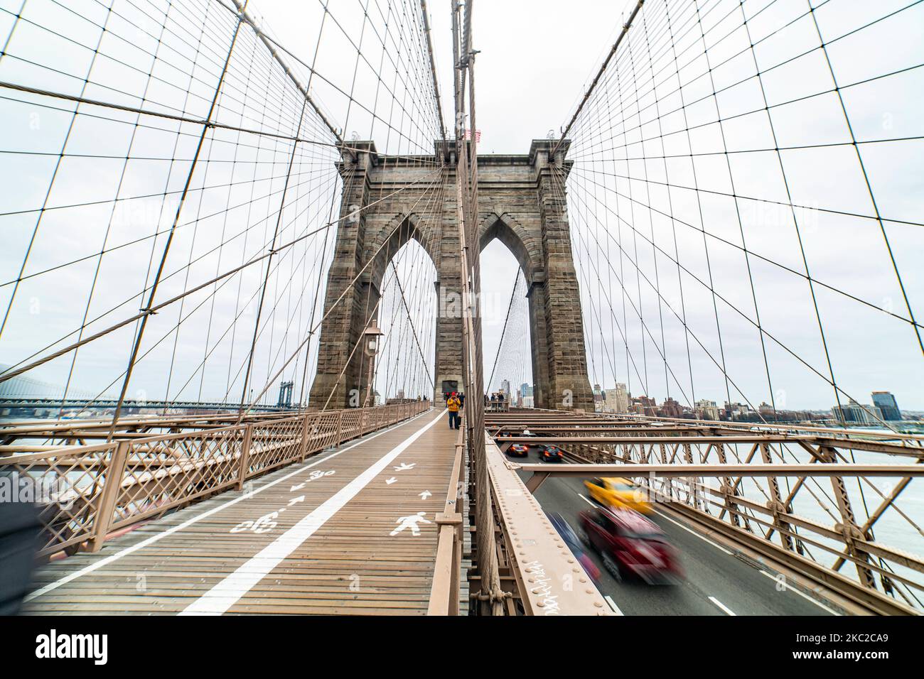 Personas y tráfico de coches desde el Puente de Brooklyn en la ciudad de Nueva York en los Estados Unidos, visto durante un día nublado con turistas y lugareños en él. El famoso puente, un punto de referencia para Nueva York y los Estados Unidos de América es un puente suspendido de cable híbrido que abarca el río East entre los distritos de Manhattan y Brooklyn. El histórico puente de Nueva York fue construido entre 1869 y 1883. Nueva York, EE.UU. El 13 de febrero de 2020 (Foto de Nicolas Economou/NurPhoto) Foto de stock