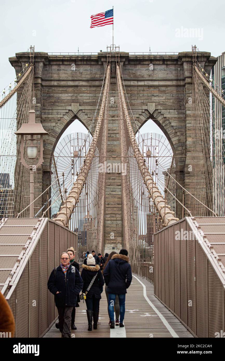 El puente de Brooklyn en la ciudad de Nueva York en los Estados Unidos, visto durante un día nublado con turistas y lugareños en él. El famoso puente, un punto de referencia para Nueva York y los Estados Unidos de América es un puente suspendido de cable híbrido que abarca el río East entre los distritos de Manhattan y Brooklyn. El histórico puente de Nueva York fue construido entre 1869 y 1883. Nueva York, EE.UU. El 13 de febrero de 2020 (Foto de Nicolas Economou/NurPhoto) Foto de stock