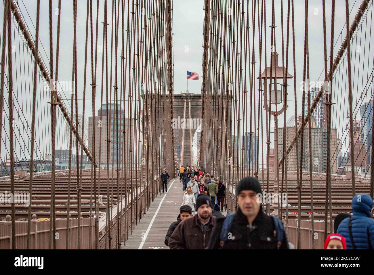 Cientos de personas en el Puente de Brooklyn en la ciudad de Nueva York en los Estados Unidos, visto durante un día nublado con turistas y lugareños en él. El famoso puente, un punto de referencia para Nueva York y los Estados Unidos de América es un puente suspendido de cable híbrido que abarca el río East entre los distritos de Manhattan y Brooklyn. El histórico puente de Nueva York fue construido entre 1869 y 1883. Nueva York, EE.UU. El 13 de febrero de 2020 (Foto de Nicolas Economou/NurPhoto) Foto de stock