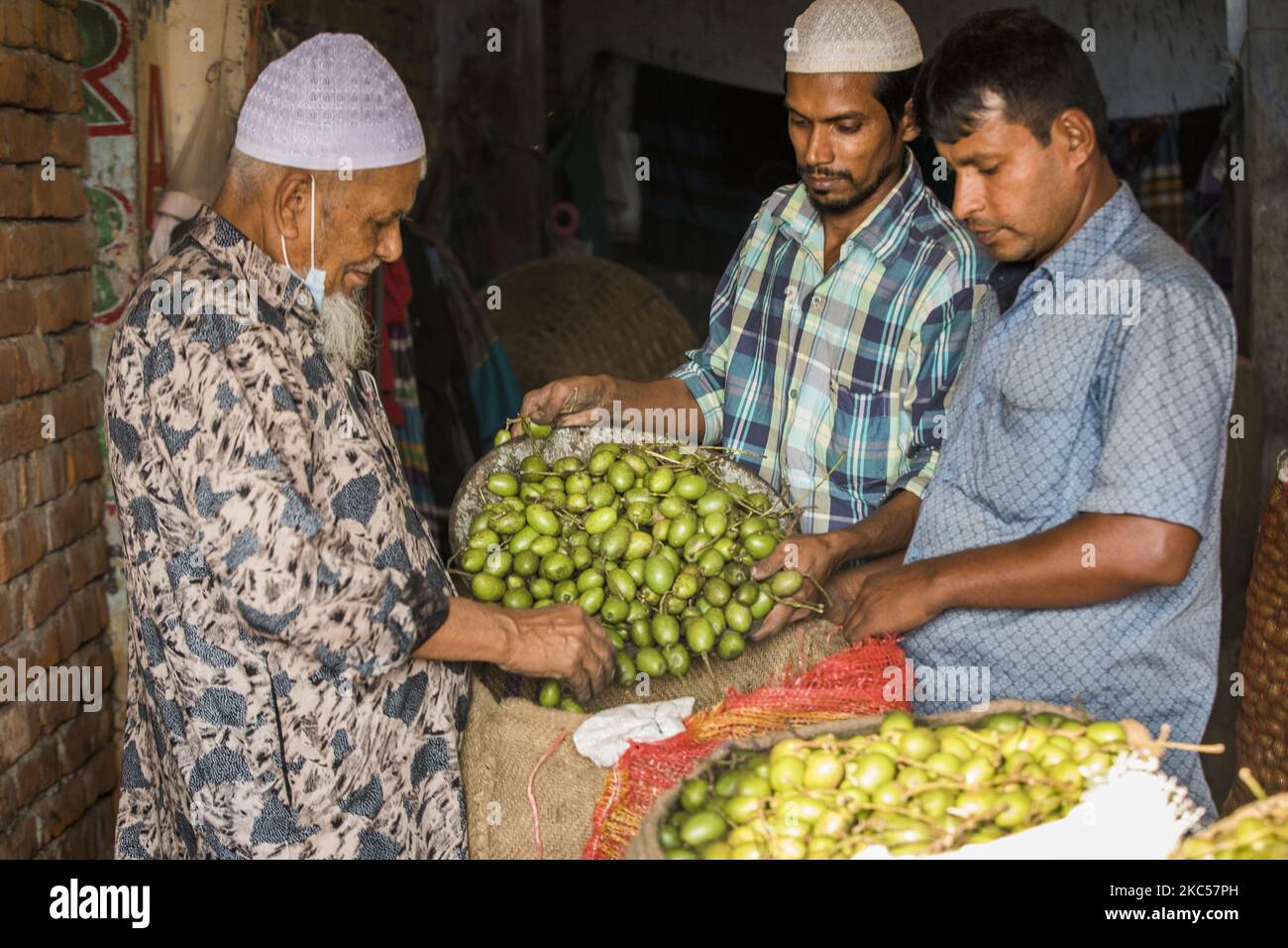Los comerciantes vieron cómo seleccionar una aceituna de un saco de yute en Sadarghat, Dhaka, Bangladesh, el 4 de diciembre de 2020. (Foto de Ahmed Salahuddin/NurPhoto) Foto de stock
