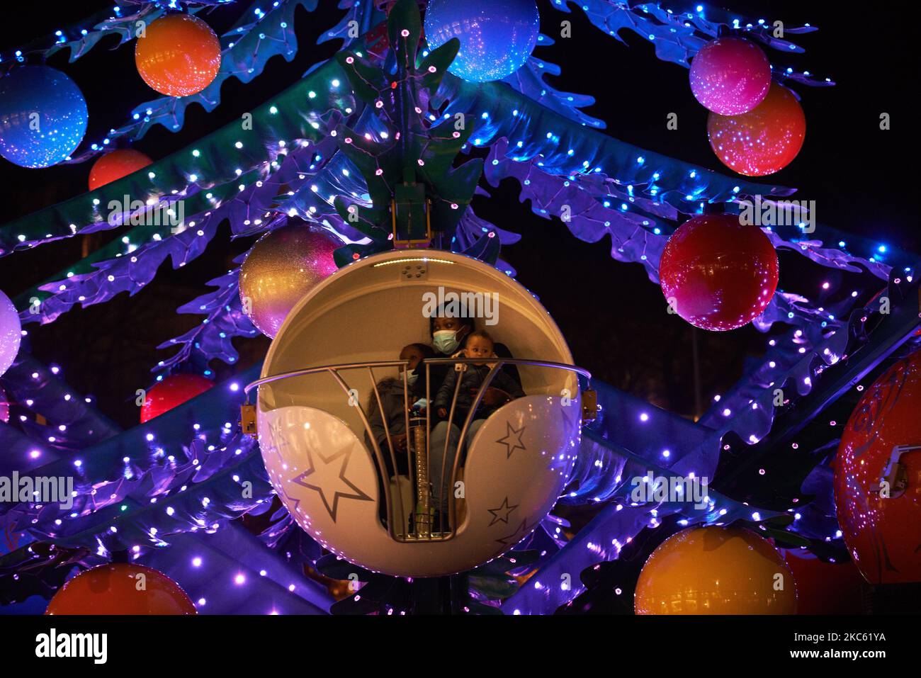 Una mujer con niños está en un alegre-go-alrededor como un árbol gigante de Navidad. A pesar de la pandemia de Covid-19 y antes del toque de queda a las 8pm, la gente disfruta de decoraciones navideñas e ir de compras en tiendas decoradas para Navidad. El ayuntamiento de toulouse, el Capitolio y la plaza del Capitolio están decorados e iluminados. Toulouse. Francia. Diciembre 16th 2020 (Foto de Alain Pitton/NurPhoto) Foto de stock