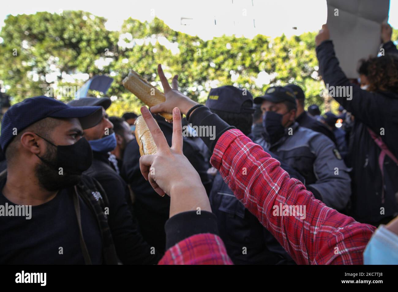 Una joven manifestante levanta un trozo de pan mientras hace cantar la victoria durante una manifestación anti-gubernamental celebrada en la avenida Habib Bourguiba, en la capital Túnez, Túnez, el 19 de enero de 2021, para protestar contra el gobierno del primer ministro Hichem Mechichi, Y en apoyo de los movimientos de protesta que golpearon a Túnez en varias ciudades de la noche a la mañana en los últimos días. Los manifestantes se enfrentaron con las fuerzas de seguridad, quienes dispararon gas lacrimógeno y utilizaron spray de pimienta para dispersarlos. También reclamaron la liberación de jóvenes detenidos por la policía durante las últimas protestas, y de deno Foto de stock