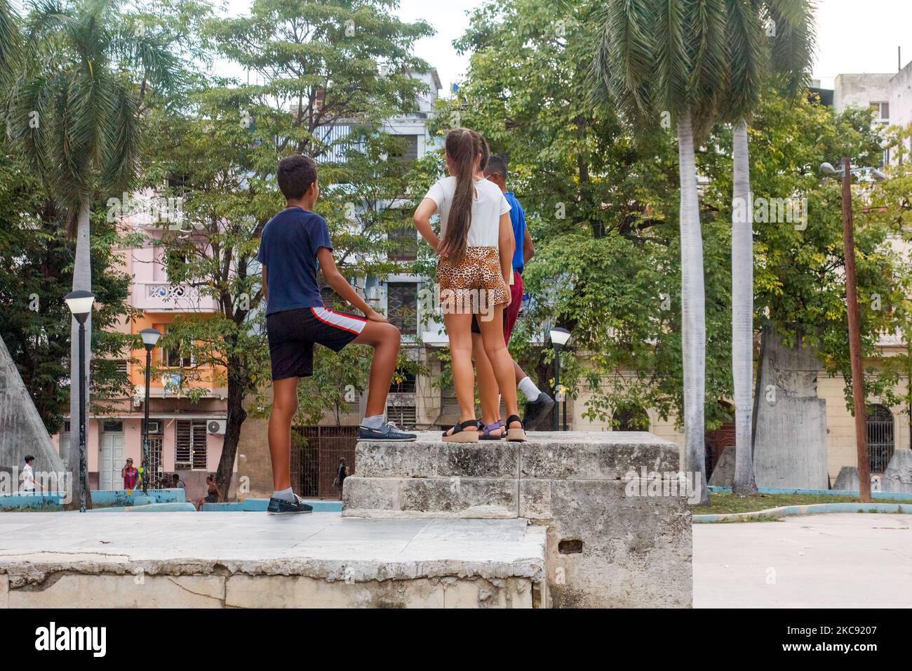Los jóvenes cubanos están en la parte superior de un muro de un parque público. Foto de stock