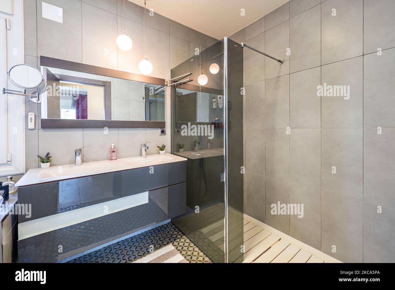 baño con espejo rectangular, armario gris y cabina de ducha con mampara de  cristal gris Fotografía de stock - Alamy