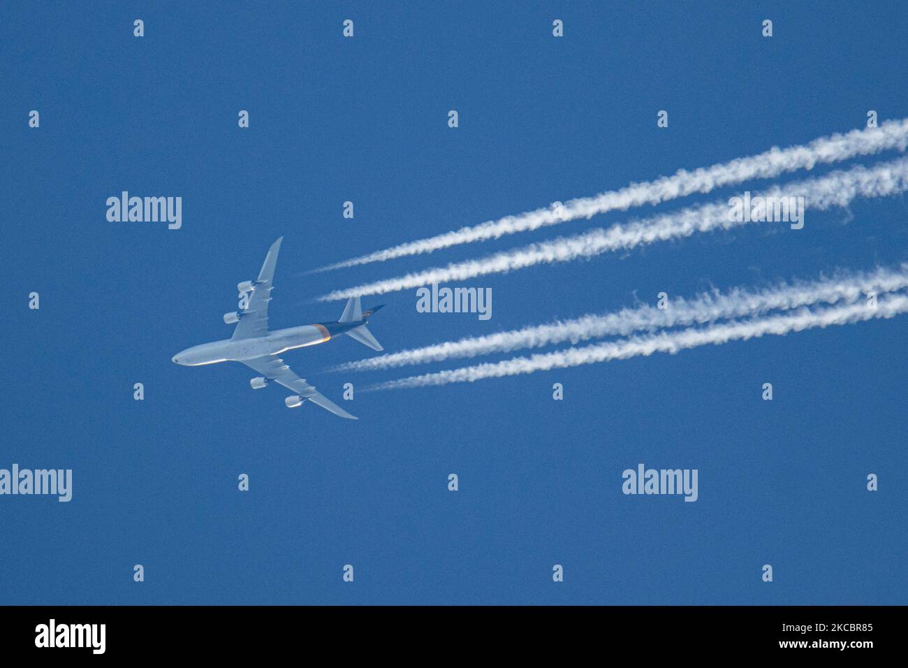 Un avión UPS Boeing 747-8F como se ve volando en el cielo azul sobre los  Países Bajos. El avión Jumbo Jet que sobrevuela está navegando a gran  altitud dejando rayas de condensación,