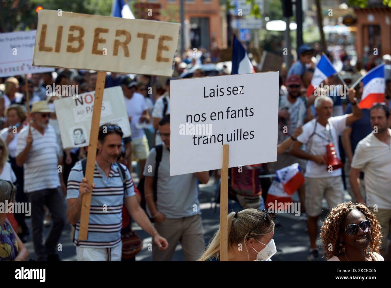 Una manifestante hembra sostiene un cartel que dice 'No toque a nuestros hijos'. Varios miles de manifestantes salieron a las calles en Toulouse contra la vacunación casi obligatoria y contra el pase de salud obligatorio después del discurso de Macron el 12th de julio. El 12th de julio, Macron anunció que el pase de salud será obligatorio para entrar a una amplia variedad de lugares públicos como cafés, teatros, salas de conciertos, cines, centros comerciales, Transporte público, piscinas e incluso hospitales a menos que se produzca una situación crítica, etc. La prohibición de espacios públicos para personas no vacunadas ha comenzado el 9th de agosto. El Pref Foto de stock