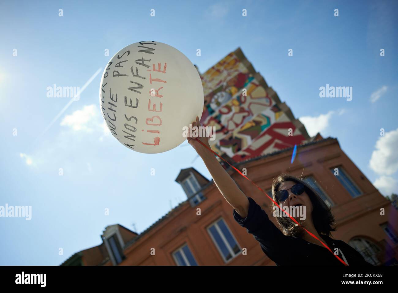 Una mujer sostiene un balón que lee 'Macron no toca a nuestros hijos. Libertad.' Varios miles de manifestantes salieron a las calles en Toulouse contra la vacunación casi obligatoria y contra el pase de salud obligatorio después del discurso de Macron el 12th de julio. El 12th de julio, Macron anunció que el pase de salud será obligatorio para entrar a una amplia variedad de lugares públicos como cafés, teatros, salas de conciertos, cines, centros comerciales, Transporte público, piscinas e incluso hospitales a menos que se produzca una situación crítica, etc. La prohibición de espacios públicos para personas no vacunadas ha comenzado el 9th de agosto. El Foto de stock