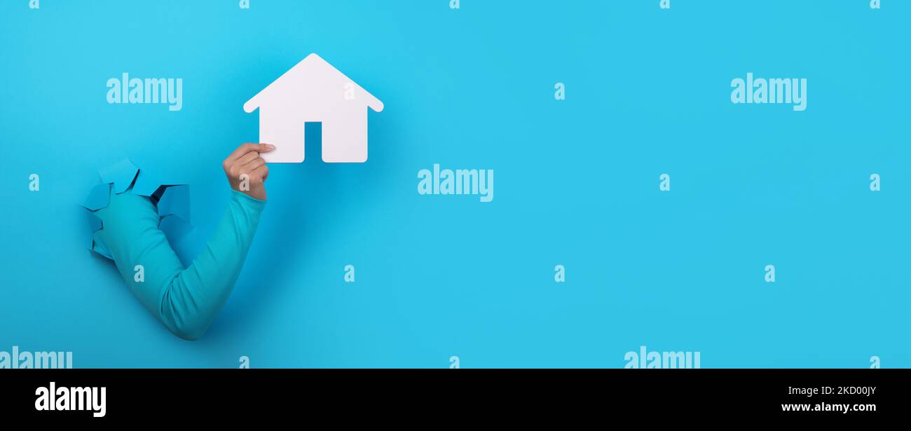 casa de mano sobre fondo azul, concepto de inversión inmobiliaria, diseño panorámico Foto de stock