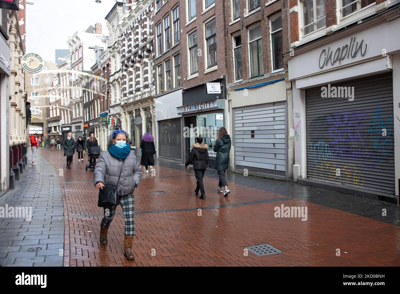 La vida diaria en la calle comercial Nieuwendijk en el centro de Ámsterdam,  con más de 200 tiendas, mientras que las personas que llevan mascarilla  pasan delante de las tiendas cerradas. Locales