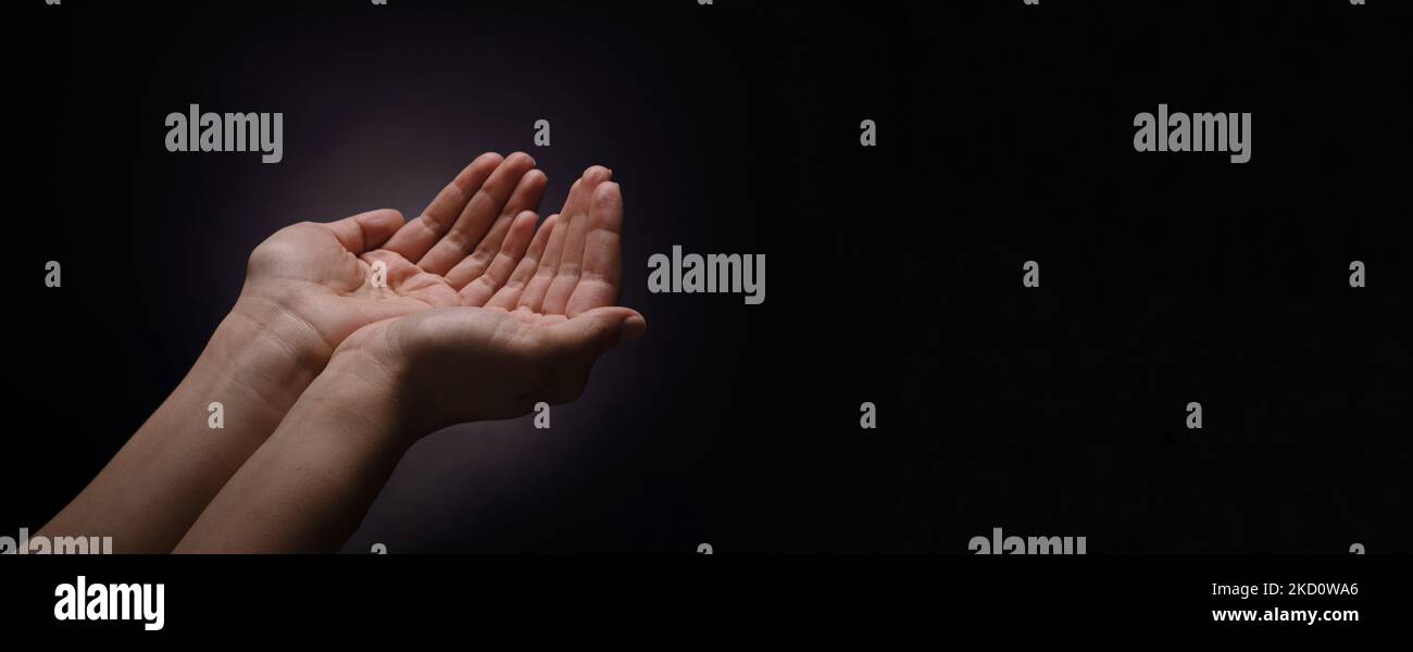 apertura de las palmas sobre fondo oscuro, gesto de mendicidad, diseño panorámico con espacio para texto Foto de stock