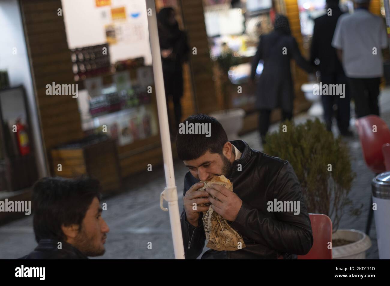 Un hombre afgano come sándwich en una calle de comida en el sur de Teherán por la noche en medio del brote de la variante Omicron del COVID-19 en Irán el 24 de enero de 2022. El Ministerio de Salud iraní anunció que la variante Omicron del coronavirus se ha extendido en una docena de provincias iraníes, Y esto mientras el Director General de la Organización Mundial de la Salud (OMS), Tedros Adhanom Ghebreyesus, ha advertido que Omicron podría conducir a un “tsunami” de casos de Covid-19 porque es más transmisible y está circulando por todo el mundo al mismo tiempo que la variante Delta. (Foto de Morteza Nikoubazl/NurPhoto) Foto de stock
