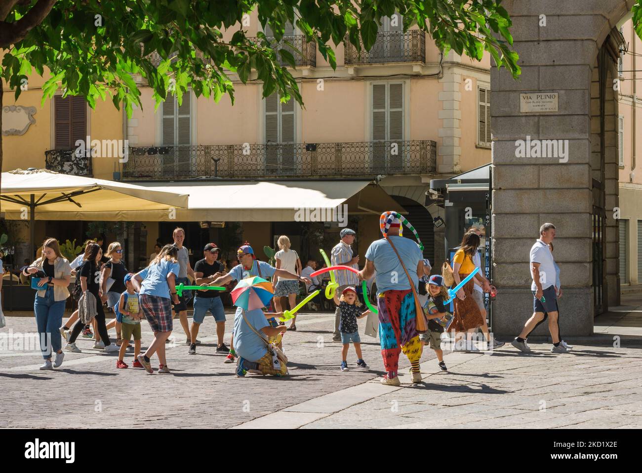 Los niños juegan, en verano los niños juegan luchando contra una banda de artistas callejeros con globos en el centro histórico de la ciudad de Como, Italia Foto de stock