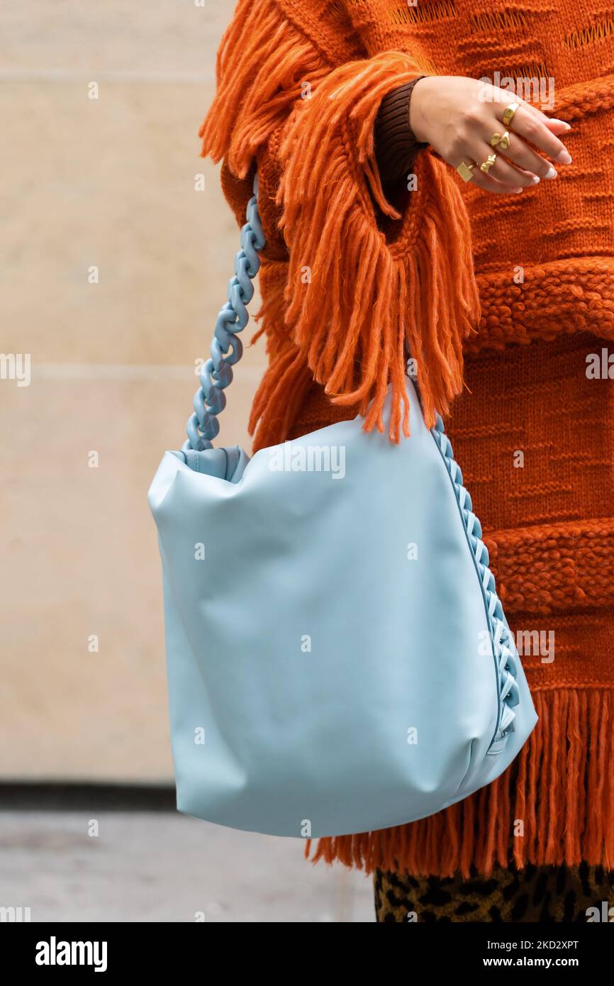 París, Francia - 3 de octubre de 2022: Una mujer viste un poncho de punto  naranja y una bolsa acolchada Falabella azul de Stella McCartney, estilo  urbano Fotografía de stock - Alamy