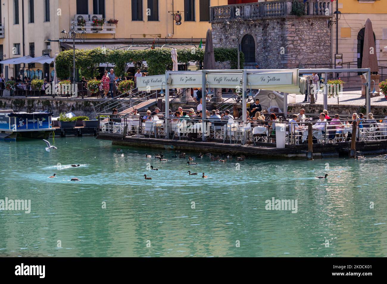 Peschiera del Garda, Verona, Italia - 22 de septiembre de 2022 Las personas disfrutan comiendo en la terraza de un restaurante flotante con hermosas vistas de Peschiera Foto de stock