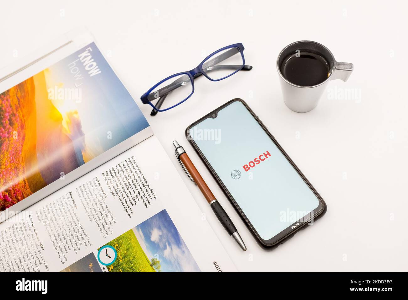 En esta ilustración fotográfica se ve un logotipo de Bosch mostrado en la pantalla de un smartphone en un escritorio junto a una cafetería, un bolígrafo, gafas y una revista en Atenas, Grecia, el 2 de julio de 2022. (Ilustración de la foto de Nikolas Kokovlis/NurPhoto) Foto de stock