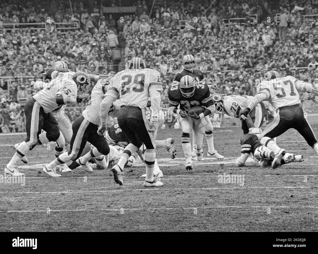 Dallas Cowboys Running Back Running Back Tony Dorsett (33) lleva el balón en el Juego del Campeonato de la NFC en el Estadio RFK en Washington, DC el sábado, 22 de enero de 1983. Defendiendo a los Redskins están el tackle defensivo de izquierda Dave Butz (65), seguridad libre Mark Murphy (29), final defensivo derecho Dexter Manley (72), y el linebacker derecho Rich Milot (57). Los Redskins ganaron el juego y un viaje al Super Bowl XVII, 31 - 17. Crédito: Ron Sachs/CNP Foto de stock
