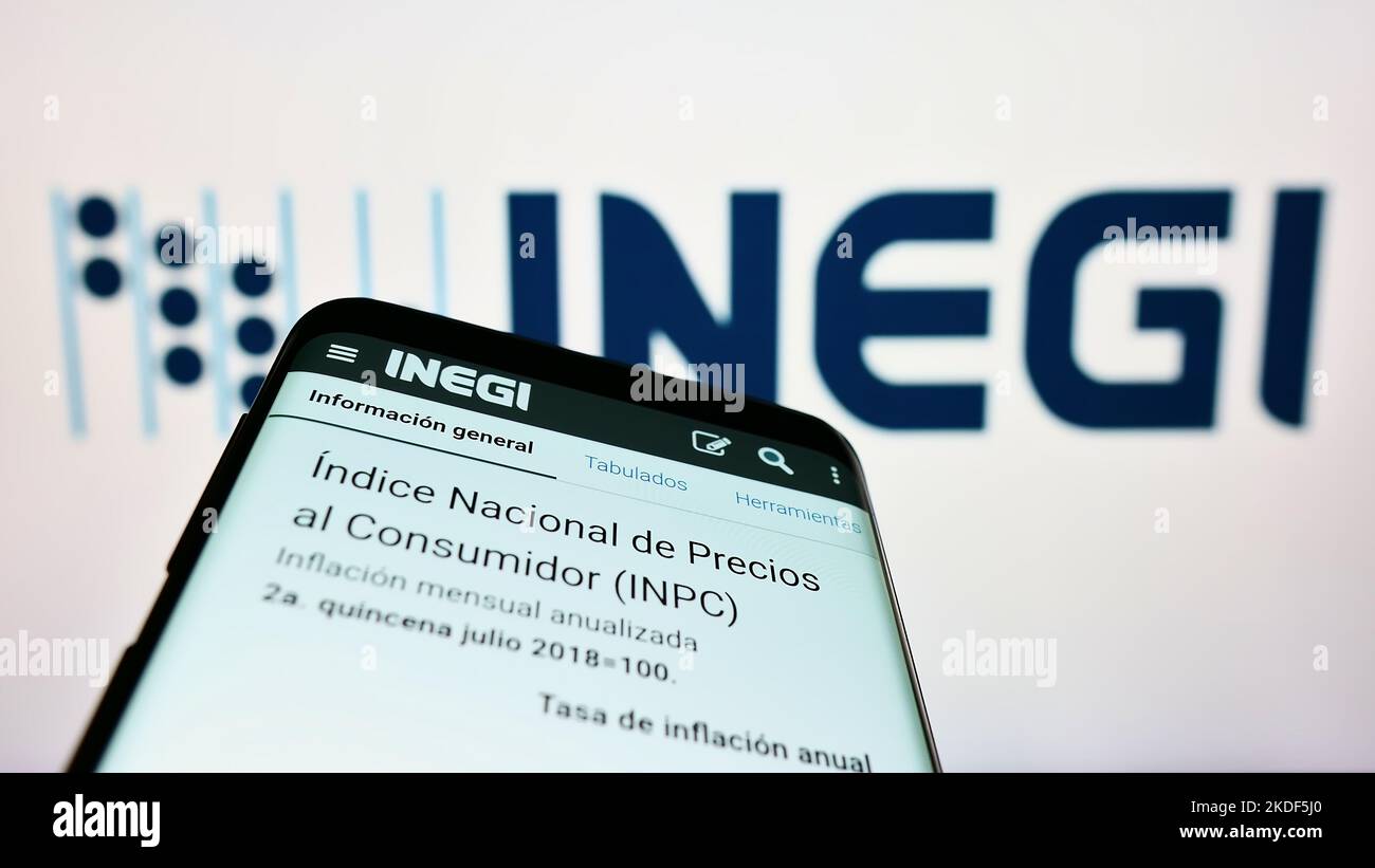 Smartphone con página web de la agencia mexicana de estadísticas INEGI en pantalla delante del logo. Enfoque en la parte superior izquierda de la pantalla del teléfono. Foto de stock
