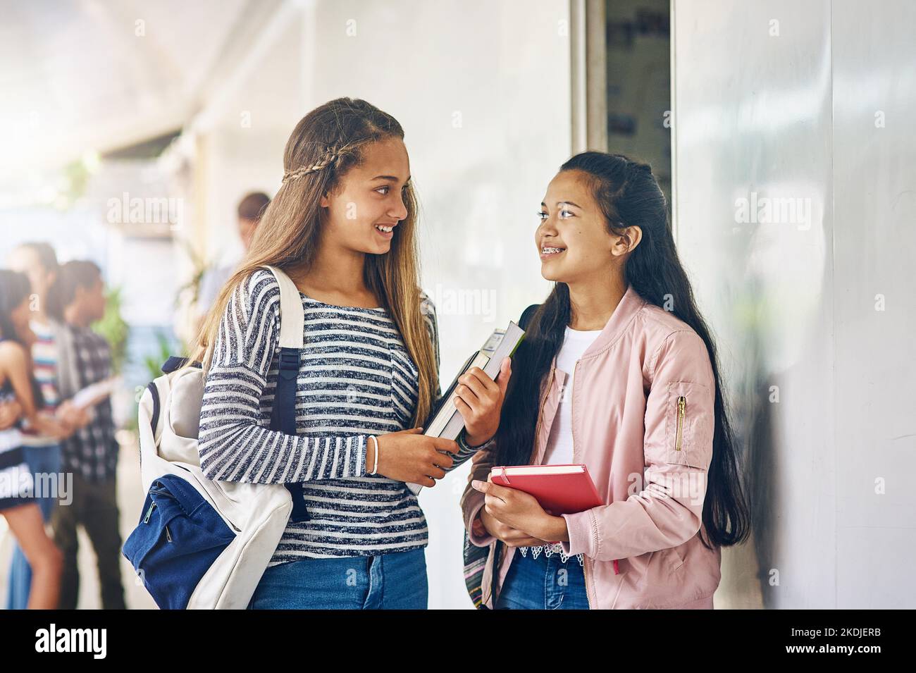 Dos niñas sonrientes con mochilas escolares. Las alumnas de 7 y 10 años  hablando en la escuela. Niña escribe en un bloc de notas Fotografía de  stock - Alamy