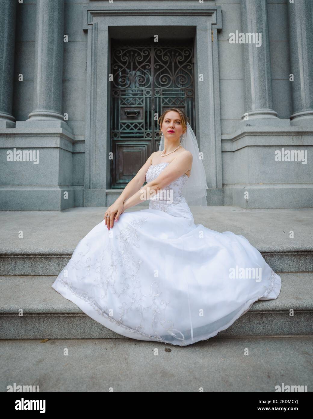 Novia con Actitud de pie frente a un edificio de granito Foto de stock