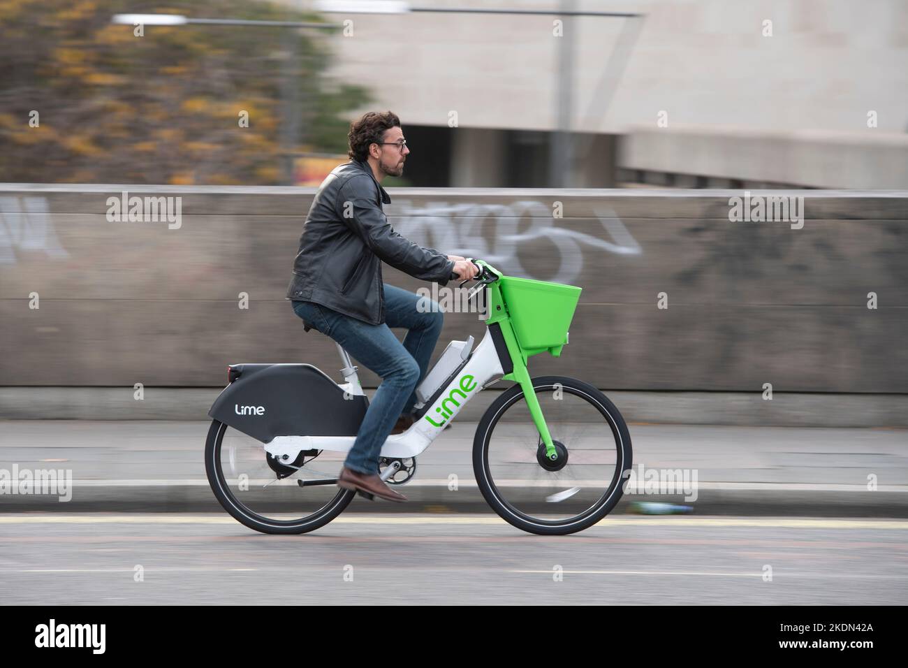 Un hombre montando una bicicleta eléctrica de alquiler Lime en Waterloo Bridge, Londres, Reino Unido. 16 de octubre de 2022 Foto de stock
